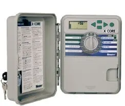 Hunter X-Core outdoor irrigation controller mounted in its plastic enclosure with door open and key in lock.