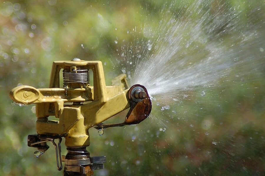 Sprinkler head dispersing water on a garden in Perth